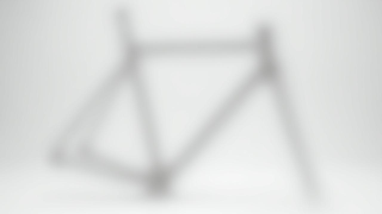 A raw, unpainted custom gravel bike frame in a studio setting, ready for hotspot interaction.